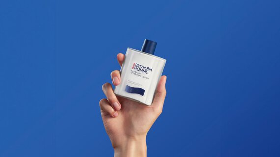 After shave emulsion in hand on blue background