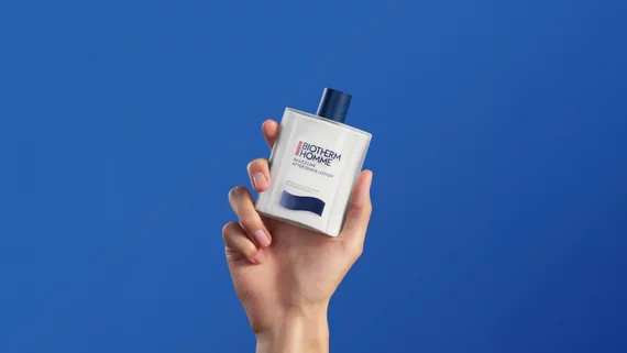 After shave emulsion in hand on blue background