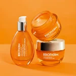 Flacone e vasetti Biotherm Aquasource+ in vetro arancione su sfondo arancione brillante, con coperchi argentati e gel idratante visibile.