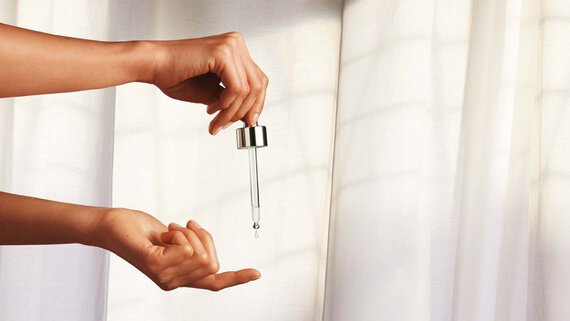 Hand holding pipette with anti-ageing serum