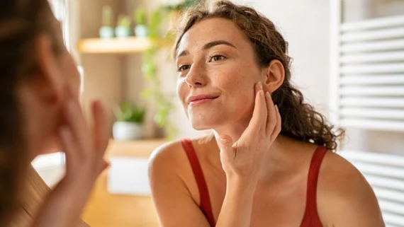 A woman examining her reflection in a mirror, focusing on her facial features and expression.