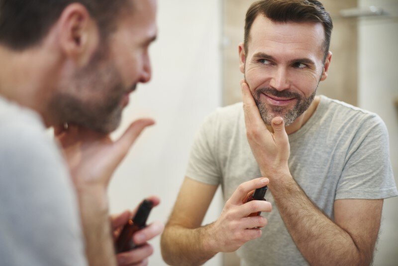 Man taking care of beard in the mirror
