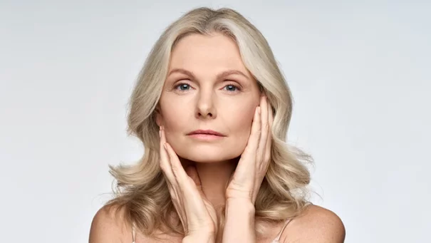 Woman against a blue background looking over her shoulder