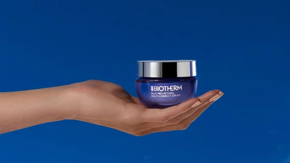 pro-retinol multi-correct crean in hand on a bleu backgroung